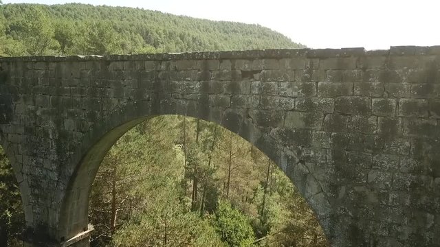 Aerial view of the Pont de la Frau, Solsona, Catalonia, Spain, Europe.
Rising, pedestal, crane shot, through arch and overthe bridge revealing the forest and mountains.