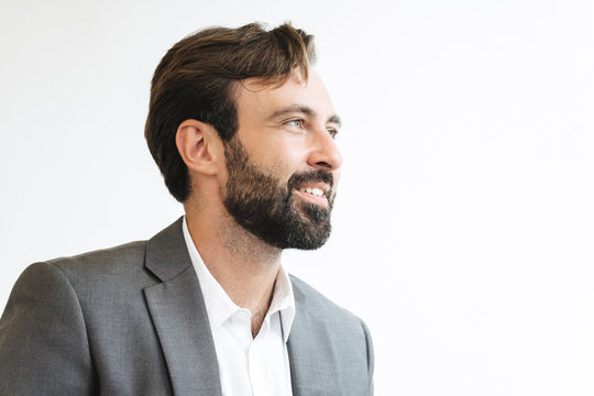 Image closeup of bearded successful businessman smiling and looking aside while working in office