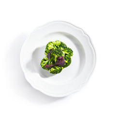 Top view of Steamed Broccoli on White Restaurant Plate Isolated