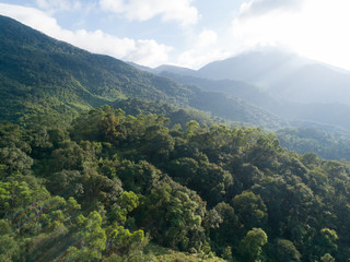 Aerial view of mountains with green dense tropical rainforests and morning fog in the sunrise