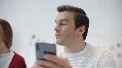 Serious man looking mobile in private house. Tired couple talking each other