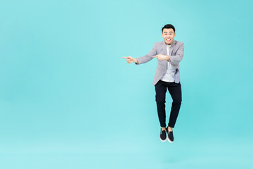 Fototapeta na wymiar Young smiling Asian man jumping and pointing hands to copy space