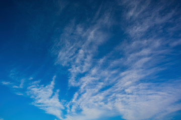 Clear blue sky with white shallow clouds diagonally, texture of the sky.