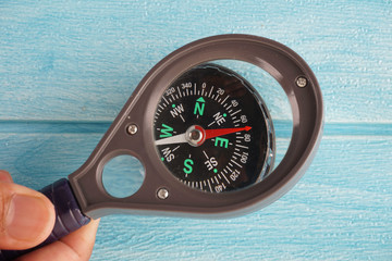 hands holding a magnifying glass on the compass. Selective focus