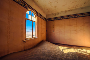 Empty room with a window and sand in the ruined ghost town Kolmanskop, Namibia