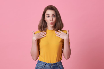 Excited beautiful woman with mouth open wearing casual yellow t-shirt isolated on pink background.