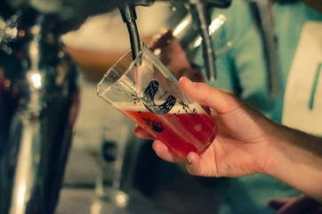 bartender pours dark beer in a glass at the bar