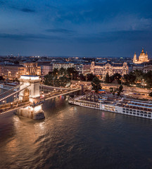 Budapest, Hungary - Aerial view of the beautiful illuminated Szechenyi Chain Bridge over River Danube at blue hour with St. Stephen's Basilica