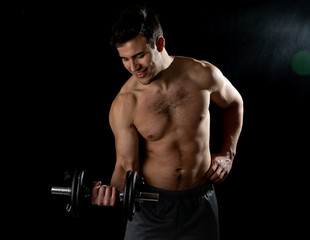 Fototapeta na wymiar young muscular man lifting weights over dark background