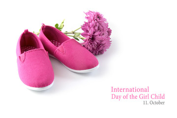 pink kid shoes and a flower isolated on a white background, text International Day of the Girl Child 11 October, copy space