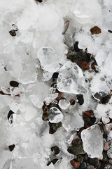 Frozen ice pebbles on the seashore. Winter season. Natural winter background.
