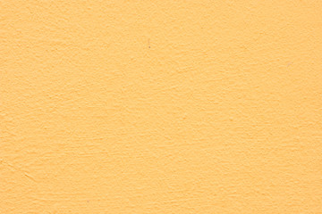 Background of a yellow stucco coated and painted exterior, rough cast of cement and concrete wall texture