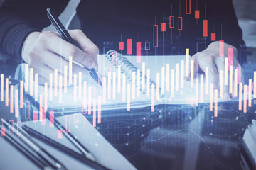 Forex chart hologram on hand taking notes background. Concept of analysis. Multi exposure