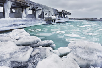 Harsh winter view of the Black Sea coast. Odessa. Huge ice floes and pier in outgrowths of ice and...