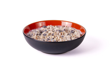 Sprouted wheat porridge with raisins and dried apricots in red and black bowl. Isolated on white background. Idea for healthy diet breakfast.