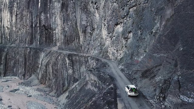 Drone Follow Shot Of Car Driving On Narrow Cliff Road