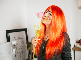 Young woman holding tulip with stickers on her face with red hair on home background. Fashion girl, pure skin concept. Festive portrait, 8 march