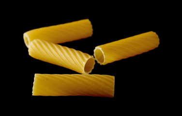 Pasta tubes, tortiglioni or elicoidali pile isolated on black background