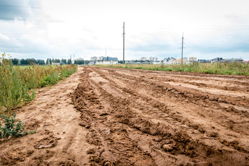 Tracks of car tires on a wet, swampy road with brown water. Country dirt road with paddles after...