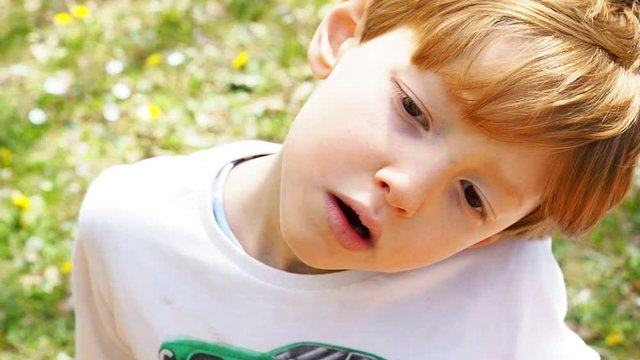 Little playful blonde boy blowing saliva bubbles outdoors