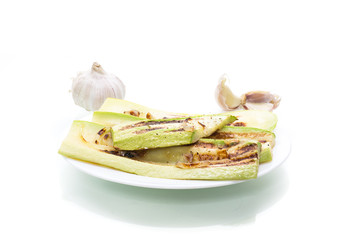 grilled zucchini with onions in a plate, isolated on white