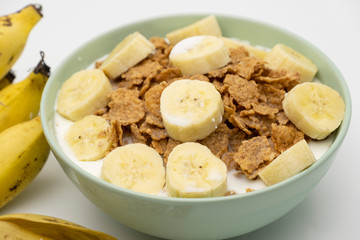 Cereal flake with pieces of banana fruits slice in the blue bowl isolated on white background