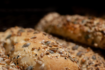 Macro photo of fresh-baked multi-grain seed buns on black background