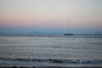 Sailboat sailing on the horizon in the light of the sunset