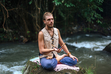 Yoga practice and meditation in nature. Man practicing near river