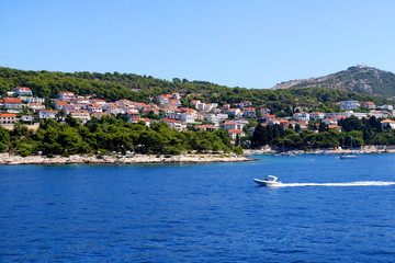 Fototapeta premium Small boat in front of town Hvar, on island Hvar, Croatia on bright summer day. Hvar is popular summer travel destination.