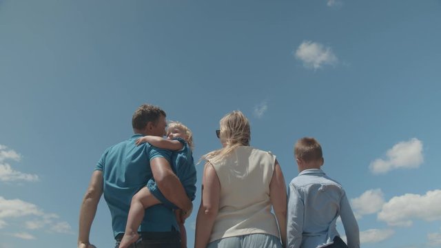 Low angle shot of family with kids waving hands to the arriving airliner flying over head