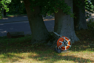 Ein aufgerollter Gartenschlauch unter einem Baum im Park...