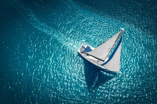 Regatta sailing ship yachts with white sails at opened sea. Aerial view of sailboat in windy condition