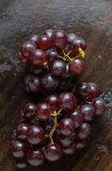 The bunch of red grape on wooden floor
