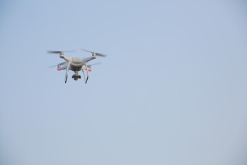White drone, quadrcopter is flying against the blue sky. With copy space for text. Equipment for aerial photography and video shooting The concept of new technologies and innovations.