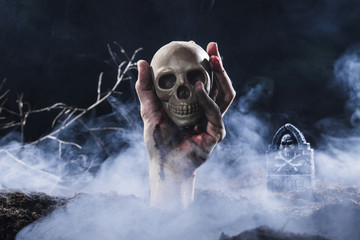 Hand sticking out of ground and holding skull