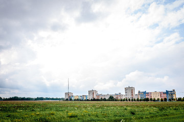 Fototapeta na wymiar Country multi-storey houses on green field and bly sky background