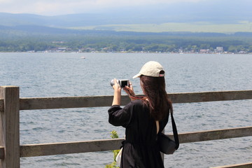 A woman is taking a photo in front of beautiful lake.