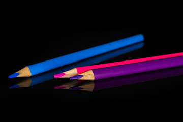 Group of three whole colored pencil cold gamma isolated on black glass