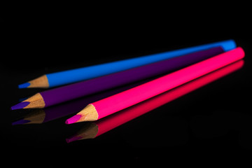 Group of three whole sharp colored pencil cold gamma isolated on black glass