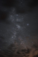 Milky way in the night sky through the clouds on a summer night