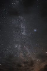 Milky way in the night sky through the clouds on a summer night