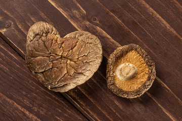 Group of two whole dry mushroom shiitake heart shape flatlay on brown wood