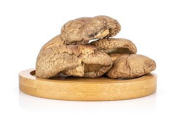 Group of four whole dry mushroom shiitake on bamboo plate isolated on white background
