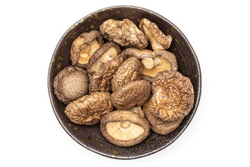 Lot of whole dry mushroom shiitake on grey ceramic plate flatlay isolated on white background