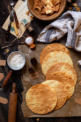 overhead shot of tasty crispy baked round puff pastry layers of homemade traditional Russian napoleon cake on parchment on rustic wooden table