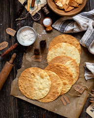 overhead shot of tasty crispy baked round puff pastry layers of homemade traditional Russian napoleon cake on parchment on rustic wooden table