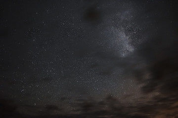 Milky way in the night sky through the clouds on a summer night