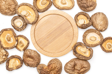 Lot of whole dry mushroom shiitake with bamboo plate in center flatlay isolated on white background