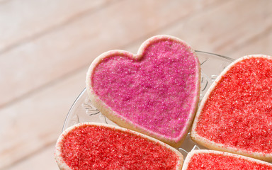 Fototapeta na wymiar Heart shaped sugar cookies with pink and red sprinkles on a plate